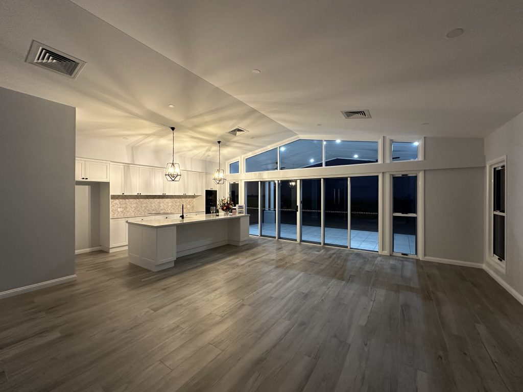New open-plan kitchen and living area with timber-look floors at dusk