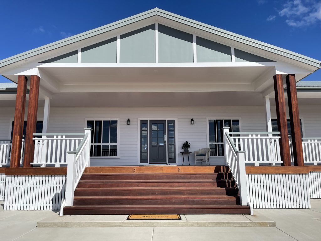 Front of a white weatherboard home with timber verandah steps