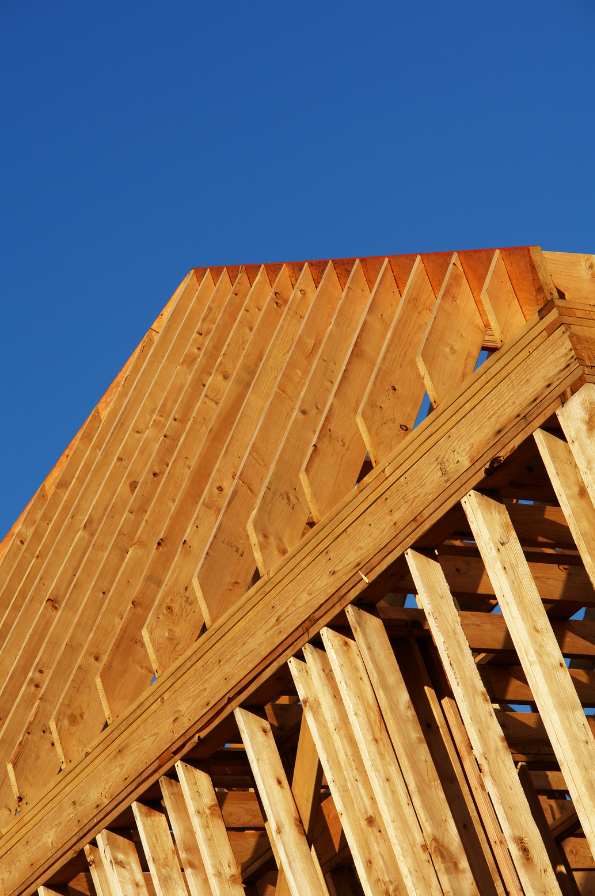 Timber roof trusses on a house frame against a blue sky