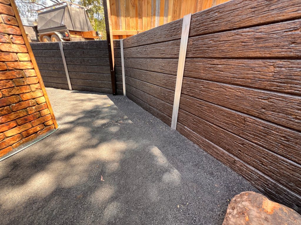 Gravel side path beside a timber-look sleeper retaining wall with steel posts